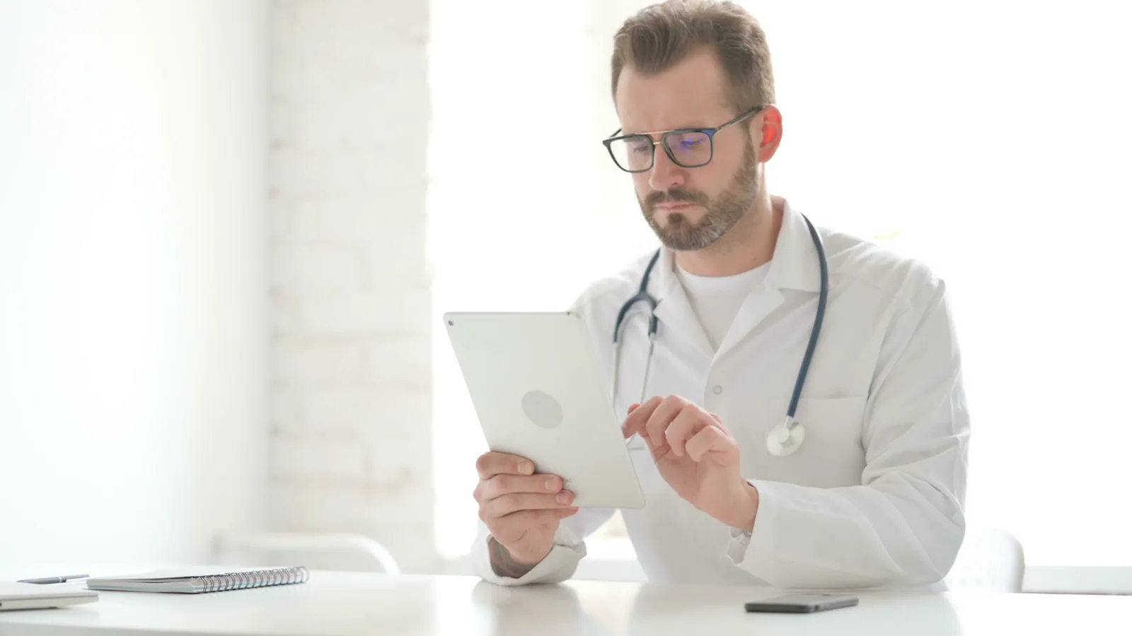 Arzt mit Tablet in einer hellen Praxis